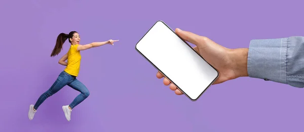 Cheerful lady jumping and pointing at empty smart phone screen — Photo