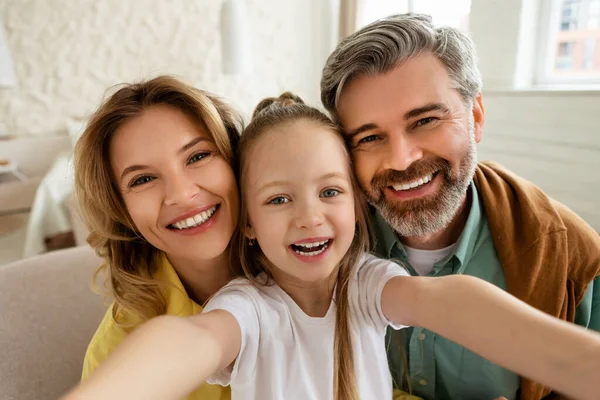 Pais felizes e filha fazendo selfie sorrindo posando em casa — Fotografia de Stock