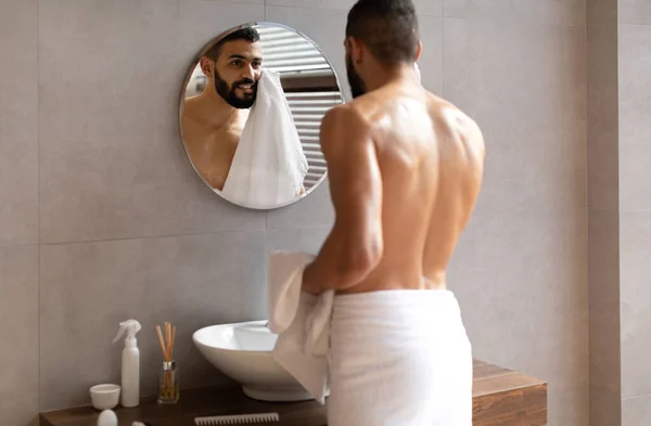Confiado joven árabe mirándose en el espejo, limpiando la cara — Foto de Stock