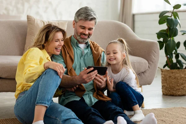 Ευτυχισμένη οικογένεια χρησιμοποιώντας Smartphone Παίζοντας Κινητό παιχνίδι στο σπίτι — Φωτογραφία Αρχείου