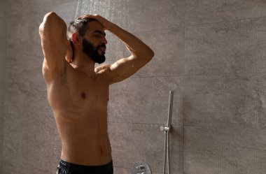 Yakışıklı, mutlu, genç Arap erkek model sıcak duşun keyfini çıkarıyor.