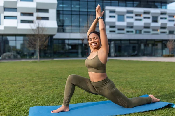 Joven mujer negra en ropa deportiva practicando yoga, haciendo ejercicios de estiramiento en el parque, espacio para copiar —  Fotos de Stock