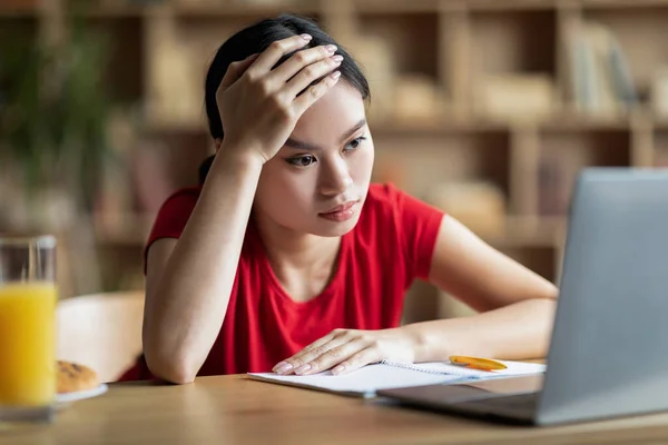 Cansado infeliz muito jovem asiático mulher estudante olhando para laptop em sala de estar interior — Fotografia de Stock