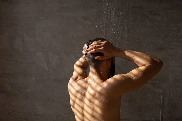 Rear back view of young man washing his body and head — Stock Photo, Image