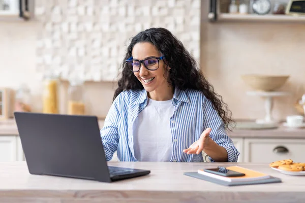 Retrato de mulher latina animado fazendo videochamada on-line com colegas ou clientes via laptop, sentado na cozinha — Fotografia de Stock