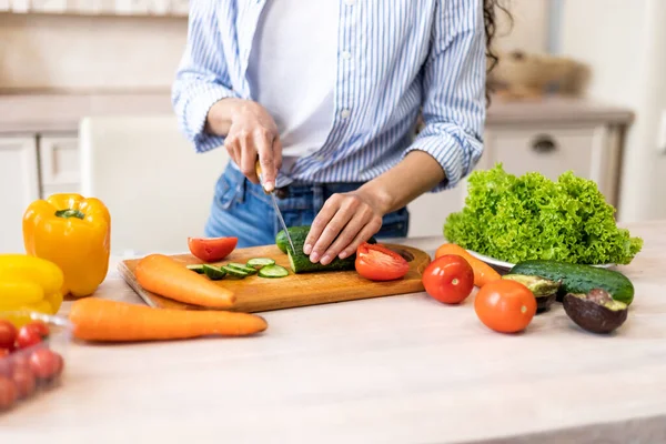 Preparación de la cena. Mujer joven cortando pepino, cocina plato de verduras, de pie en la cocina en casa, primer plano — Foto de Stock