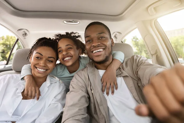 Alegre família negra abraçando sentado em novo carro de férias — Fotografia de Stock