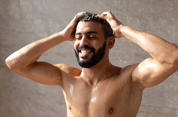 Красивый улыбающийся молодой арабский мужчина-модель принимает горячий душ — стоковое фото