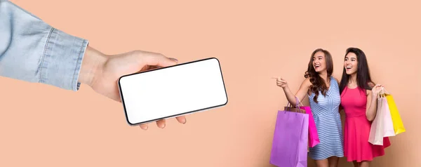 Frauen posieren mit weißem, leeren Smartphone-Bildschirm und Einkaufstaschen — Stockfoto