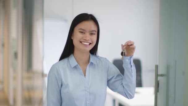 Concepto inmobiliario. Joven profesional asiático mujer agente inmobiliario mostrando llaves de nuevo hogar y sonriendo a la cámara — Vídeos de Stock