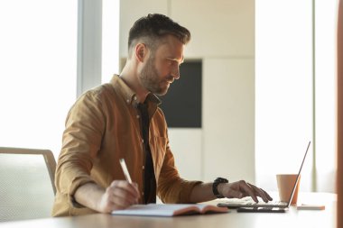 İşadamı İşyeri, Yan Görünüm 'de Dizüstü bilgisayar kullanarak not alıyor