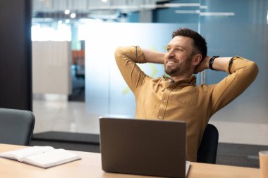 Neşeli İş Adamı Modern Ofiste Dizüstü bilgisayarın yanında Rahatlıyor