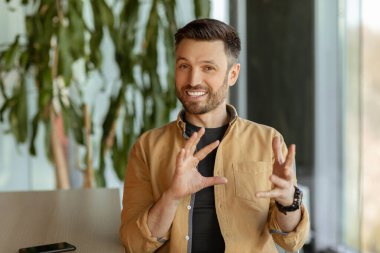 İş adamı kameraya bakıp ofiste video görüşmesi yapıyor.