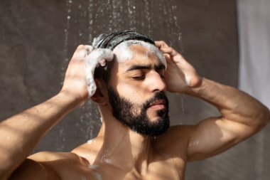 Yakışıklı genç Arap erkek model sıcak duş almanın keyfini çıkarıyor.