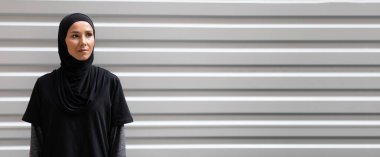 Gerçekten sakin, tesettürlü genç bir Arap kadın boş alana bakıyor, kardiyo çalışmasına hazır.