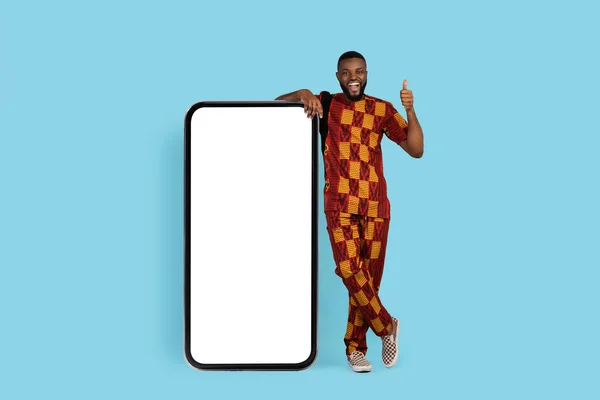 令人惊奇的报价。站在空白智能手机附近的传统服饰中兴奋的黑人男性 — 图库照片