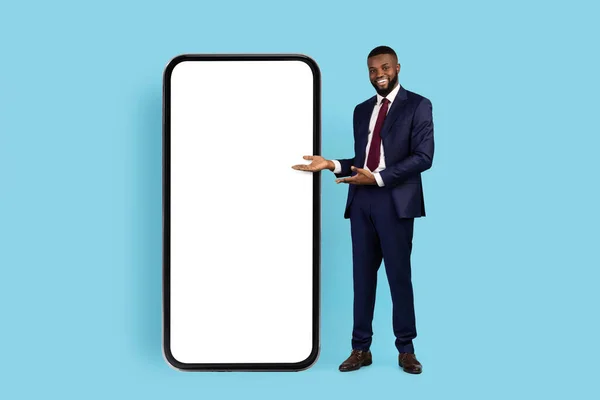 Úspěšný černý podnikatel ukazující na velký smartphone s bílou prázdnou obrazovkou — Stock fotografie
