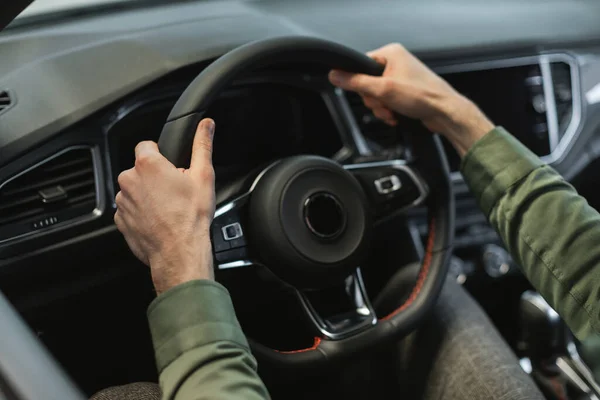 Vue rapprochée du jeune homme tenant volant de la voiture de luxe moderne, en cours d'essai routier chez le concessionnaire automobile moderne — Photo