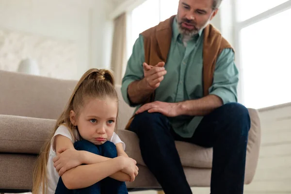 Padre estricto regañando triste pequeña hija sentada en casa — Foto de Stock