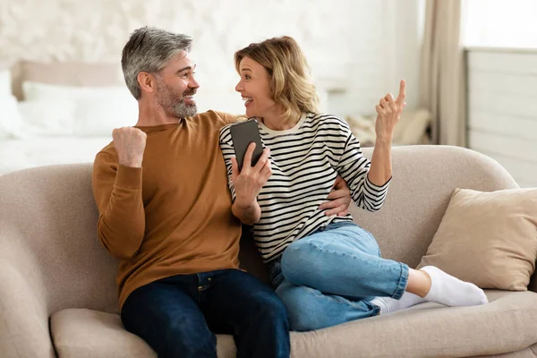 Couple joyeux utilisant un téléphone portable et gestuelle Oui à la maison — Photo