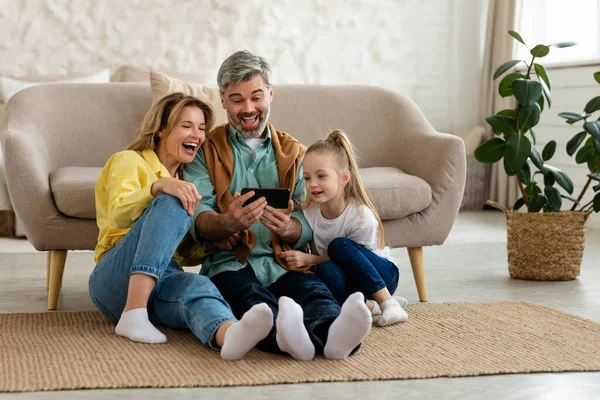 Χαρούμενη οικογένεια που χρησιμοποιεί το κινητό τηλέφωνο Γέλιο Περιήγηση στο Internet στο σπίτι — Φωτογραφία Αρχείου