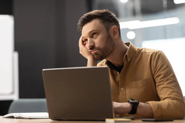 Uomo d'affari infelice seduto vicino al computer portatile che ha problemi in ufficio — Foto Stock