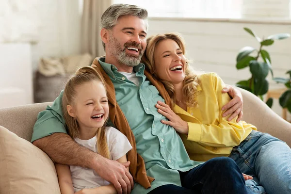 Parents du Moyen Âge et fille étreignant assis sur le canapé intérieur — Photo