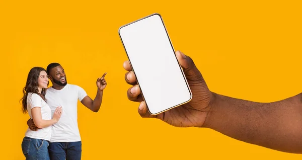 Pareja interracial mostrando pantalla vacía de teléfono inteligente en blanco para maqueta — Foto de Stock