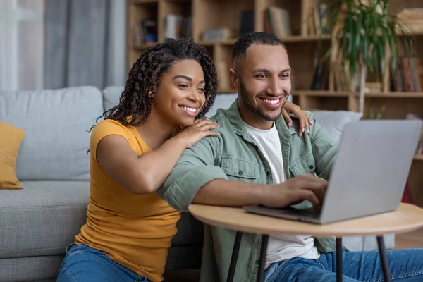 Marido y esposa afroamericanos felices usando el ordenador portátil, navegar por Internet, descansar juntos en casa —  Fotos de Stock