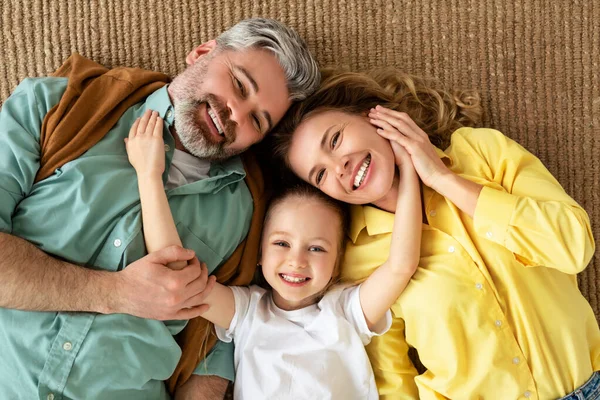 Feliz família abraço deitado no chão sorrindo para câmera interior — Fotografia de Stock