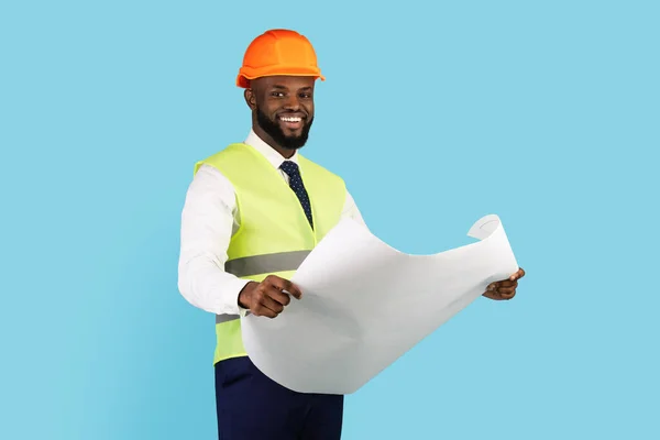 Sorridente appaltatore afroamericano che tiene progetti mentre è in piedi isolato su sfondo blu — Foto Stock