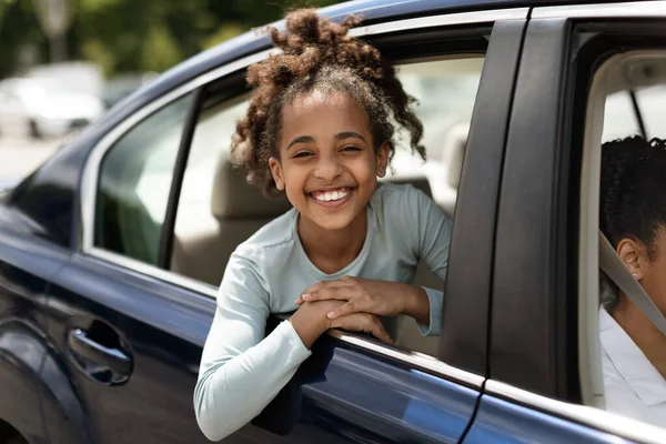 Счастливая чернокожая девочка выглядывает из окна автомобиля — стоковое фото