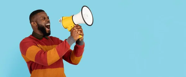 Portrait of Young African American Man With Megaphone In Hands Making Announcement, Black millial Male Shouting Aside At Copy Space On Blue Background, Using Loudspeaker To Share News, Panorama — 스톡 사진