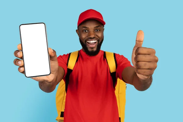 Чудовий додаток. Чорний хлопець доставки тримає порожній смартфон і показує великий палець вгору — стокове фото