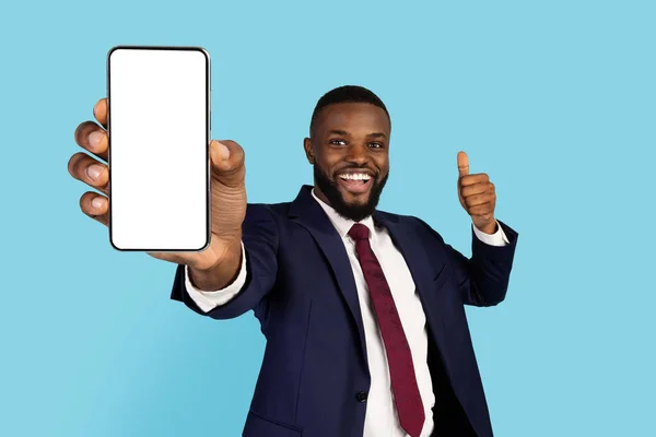 Alegre hombre de negocios afroamericano sosteniendo un gran teléfono inteligente en blanco y mostrando Pulgar hacia arriba —  Fotos de Stock