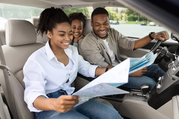 Familia negra feliz sentada en el coche mirando la hoja de ruta —  Fotos de Stock