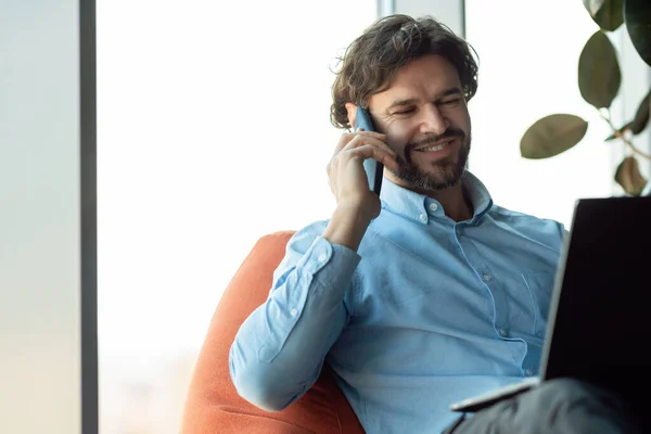 Leende man som jobbar och pratar i mobiltelefon på kontoret — Stockfoto