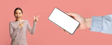 Asyalı kadın beyaz, boş akıllı telefon ekranını işaret ediyor.