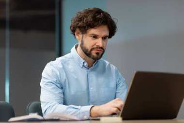 İşadamı koltukta dizüstü bilgisayar kullanıyor.