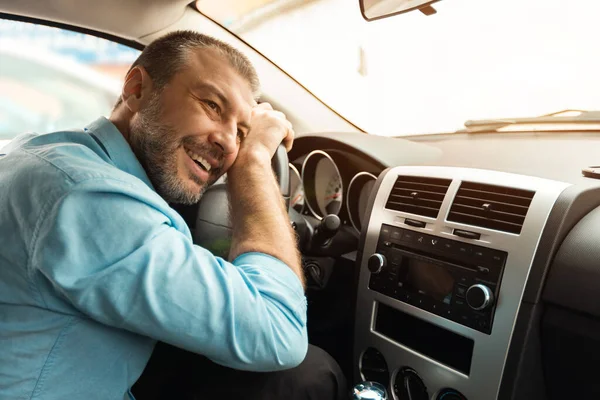 Happy guy hugging steering wheel sitting inside his new vehicle