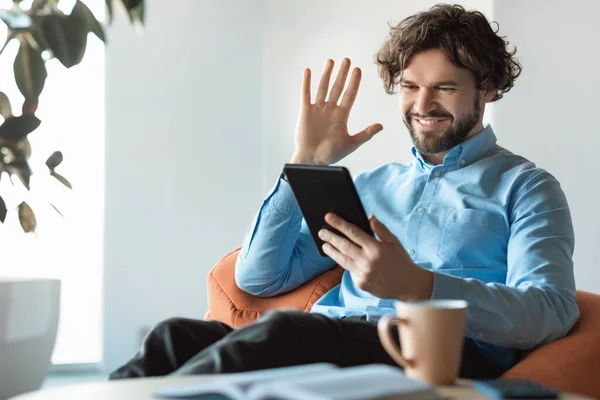 Hombre de negocios usando tableta saludando la mano haciendo videollamada — Foto de Stock