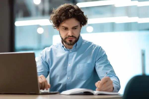 Retrato de empresário focado usando laptop e escrita — Fotografia de Stock