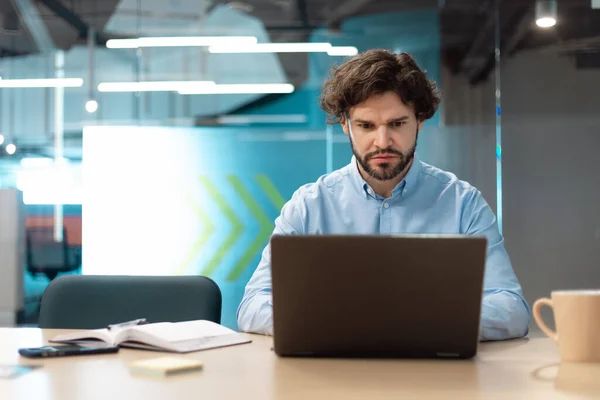 Zakenman met laptop zittend op stoel in modern kantoor — Stockfoto