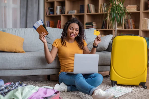 Bilhetes online reserva. Mulher negra excitada com passaporte e passagens de avião usando laptop para comprar férias turísticas — Fotografia de Stock