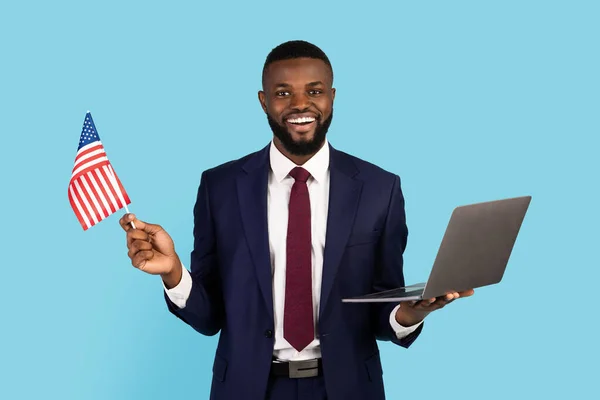 École de commerce en ligne. noir sourire homme d'affaires tenant ordinateur portable et drapeau des États-Unis — Photo
