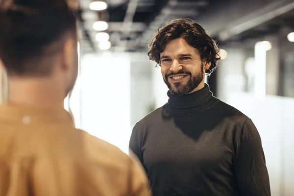 Dostça gülümseyen erkek meslektaşlar, şirket binasında yüz yüze toplanıyorlar. İş birliği kavramı — Stok fotoğraf