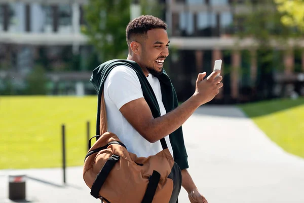 Sorrindo homem negro usando telefone andando na cidade — Fotografia de Stock