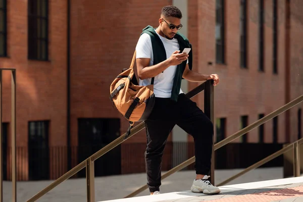 Jovem negro usando telefone andando na cidade — Fotografia de Stock