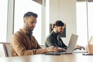 Odaklanmış şirket çalışanları dizüstü bilgisayar kullanıyorlar, modern ofiste birlikte çalışıyorlar, uzayı kopyalıyorlar. Eş çalışma kavramı