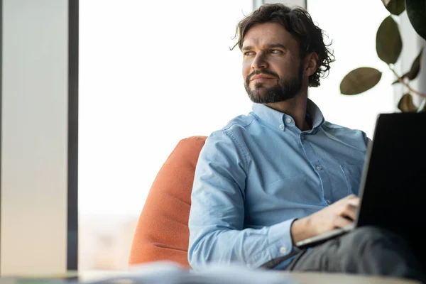 Affärsman som använder bärbar dator sittande på bönpåse på kontoret — Stockfoto